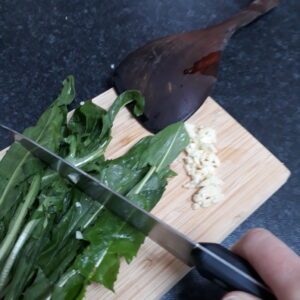 Chopping dandelion leaves with garlic